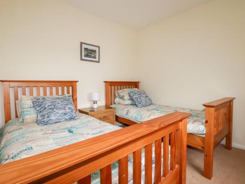 a bedroom with two beds and a wooden bed frame at 2 Old Talbot Cottages in Lostwithiel