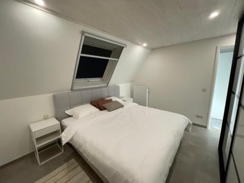 - une chambre blanche avec un grand lit et une fenêtre dans l'établissement Vakantieverblijf De Munt, à Oudenburg