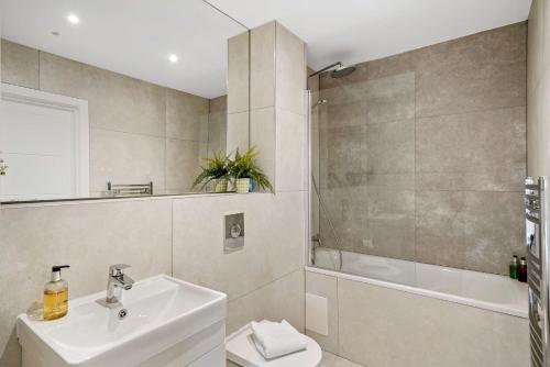 a bathroom with a sink and a toilet and a tub at The Arches Watford in Watford