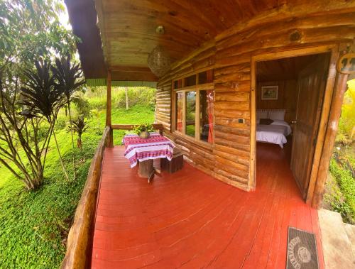 Holzhütte mit einem Bett und einem Tisch auf einer Terrasse in der Unterkunft Cabañas Palma Sky Lodge in Oxapampa