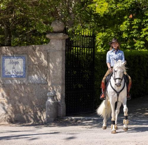 a woman riding a white horse down a street at O Cantinho da Penetra AL in Santar
