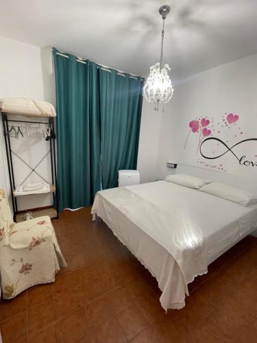 1 dormitorio con cama blanca y lámpara de araña en La terrazza sul MARE Manfredonia, en Manfredonia