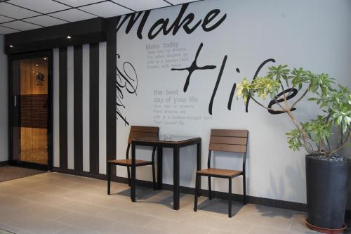 two tables and two chairs against a wall with a make sign at Grace Hotel in Taipei