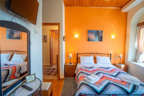 a bedroom with two beds with orange walls and a mirror at Gkoura hotel in Sirako