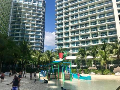 uma praia com um parque infantil em frente a um grande edifício em Azure Urban Resort Residences 2-BR Balcony Amenity View by Casa Rafael em Manila