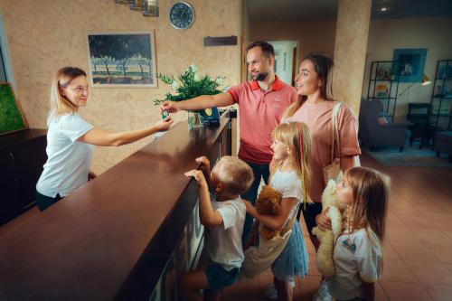 una famiglia che si trova in piedi accanto a un bancone in un soggiorno di Zacisze Nad Nidą Resort a Pińczów