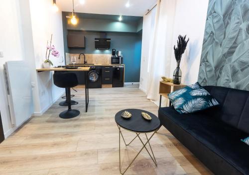 un salon avec un canapé noir et une cuisine dans l'établissement Le Cinq : Appartement Chic&Cosy, jardin privatif, à Vesoul