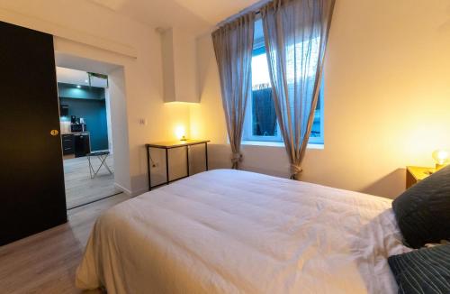 um quarto com uma grande cama branca e uma janela em Le Cinq : Appartement Chic&Cosy, jardin privatif em Vesoul