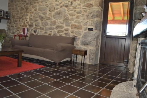 a living room with a couch and a stone wall at Airiños de Mondariz in Mondariz