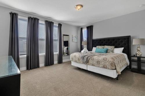 a bedroom with a bed and windows and a television at 451-Luxury Villa wMovie Theater and Arcade in Orlando