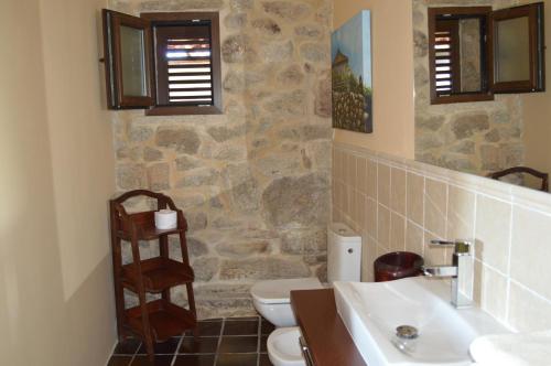 baño con 2 lavabos, aseo y pared de piedra en Airiños de Mondariz, en Mondariz