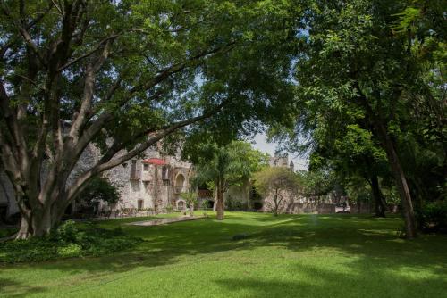 a park with trees in front of a building at Hotel Hacienda Vista Hermosa in Tequesquitengo