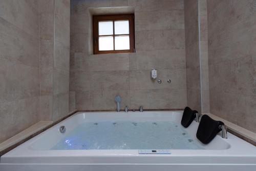 a large white tub in a bathroom with a window at Hotel Castello in Prizren
