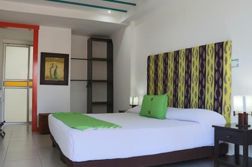 a bedroom with a large white bed with a green headboard at Hotel Campestre La Tata in Montenegro