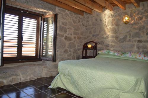1 dormitorio con cama y pared de piedra en Airiños de Mondariz, en Mondariz
