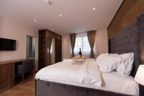 a bedroom with a large white bed and a desk at Hotel Castello in Prizren