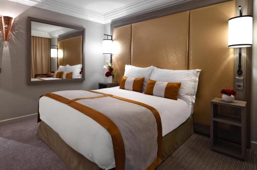 a hotel room with a large bed and a mirror at Mövenpick Hotel Mansour Eddahbi Marrakech in Marrakech