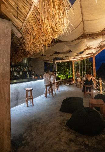 a restaurant with people sitting in chairs under a straw roof at Maya Tulum By G Hotels in Tulum