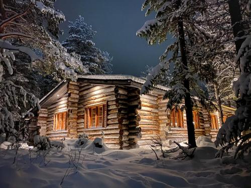 uma cabana de madeira na neve à noite em Cottis - Kultakettu em Levi