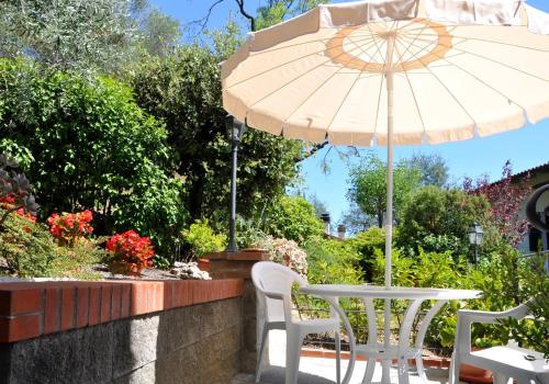 a white table and chairs with an umbrella at La Collina del Melograno in Sinalunga