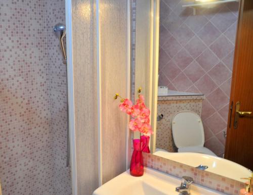 a bathroom with a vase of flowers on a sink at La Collina del Melograno in Sinalunga