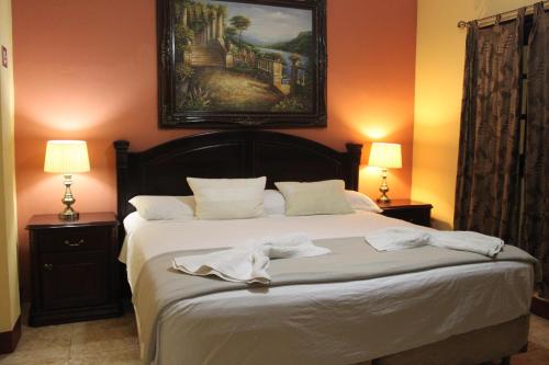 a bedroom with a bed with a painting on the wall at Hotel Guardabarranco in Granada