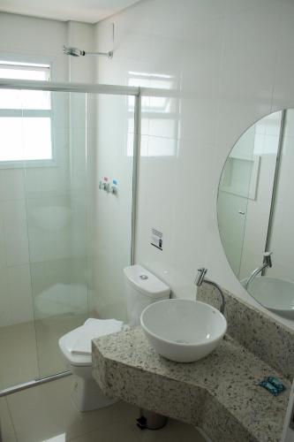 a bathroom with a sink and a toilet and a mirror at Hotel Seville Comfort in Telêmaco Borba