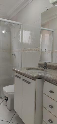 uma casa de banho com um WC, um lavatório e um espelho. em Incrível apartamento Balneário Camboriú em Balneário Camboriú