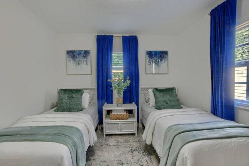 two beds in a room with blue curtains at Boynton Beach Getaway in Boynton Beach