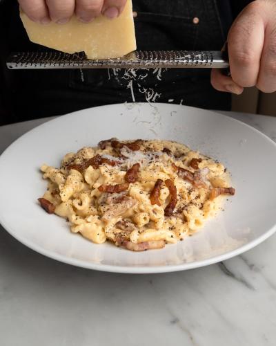 a plate of pasta with bacon and cheese on a table at Century Plaza Hotel in Vancouver
