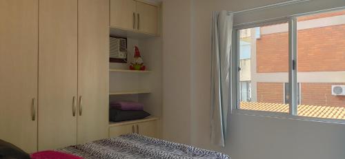 een slaapkamer met een raam en een bed met een deken bij Incrível apartamento Balneário Camboriú in Balneário Camboriú