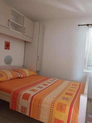 sypialnia z łóżkiem z pomarańczowym i żółtym kocem w obiekcie Volat Apartments w mieście Betina