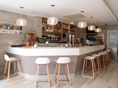 a bar with white stools in a restaurant at Hospedium Hotel Abril in San Juan de Alicante