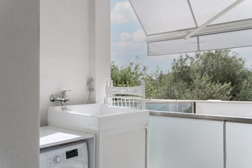ein weißes Bad mit einem Waschbecken und einem Fenster in der Unterkunft LOUXORY ACCOMODATION CAGLIARI in Cagliari