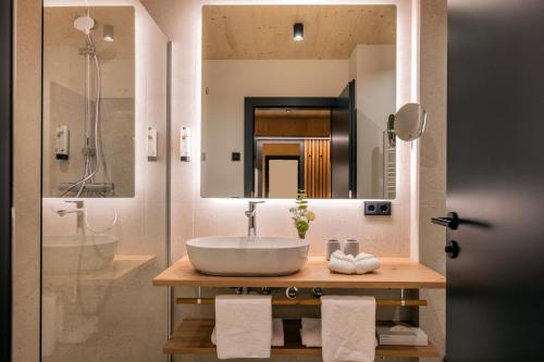 ein Bad mit einem Waschbecken und einem Spiegel in der Unterkunft Der Dolomitenhof - Tristach in Lienz