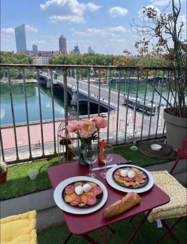une table avec deux assiettes de nourriture sur un balcon dans l'établissement Coeur de Lyon avec Terrasse et Jacuzzi, à Lyon