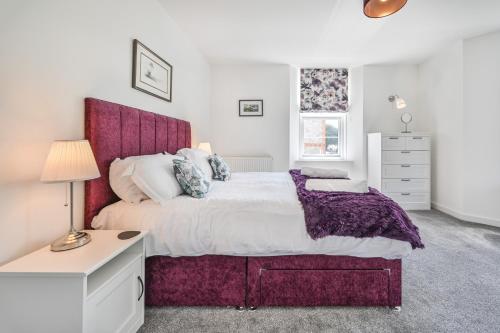 a bedroom with a large bed with a purple headboard at The Falstone Apartment in Torquay