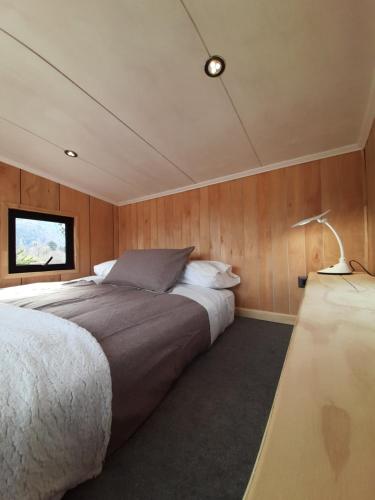 1 dormitorio en un barco con 1 cama y 1 lámpara en Rucautín Tiny Cabin en Malalcahuello
