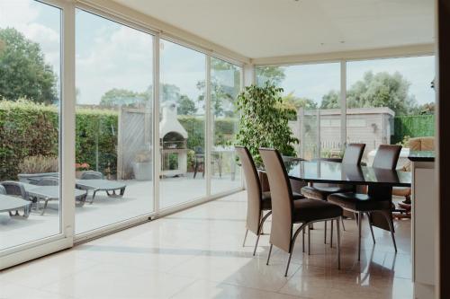 een eetkamer met glazen deuren en een tafel en stoelen bij Villa Fortem męt sauna en jacuzzi in Alveringem