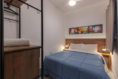 een slaapkamer met een blauw bed en een spiegel bij Apartamento completo no Brás in Sao Paulo