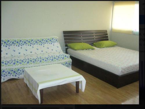 1 dormitorio con 2 camas, banco y mesa en Room in Guest room - Impact Don Mueang Bangkok Guest House, en Thung Si Kan