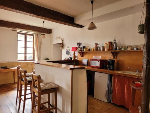 - une cuisine avec un comptoir et quelques chaises dans l'établissement Grande maison de montagne rénovée, du charme, à Rodome