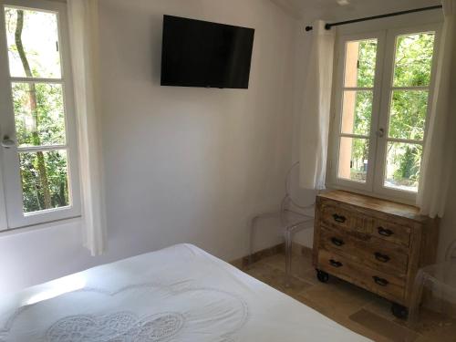a bedroom with a bed and a television on the wall at Les Mazets de la Cascade in Salernes