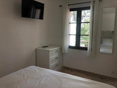 a white bedroom with a bed and a window at Les Mazets de la Cascade in Salernes