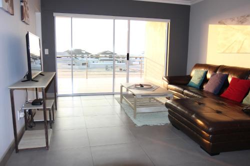 a living room with a leather couch and a table at Atlantic Dunes Unit 10, Self Catering in Rand Rifles