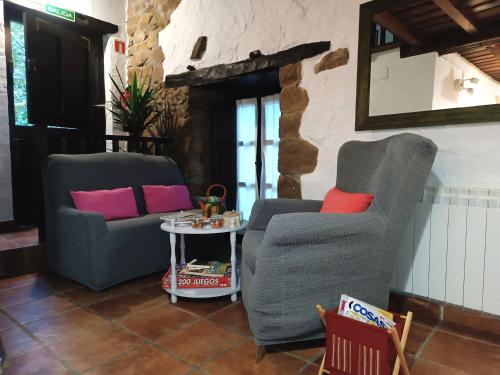 two chairs and a table in a living room at La Nozal - La Vallicuerra Casas Rurales in Mieres