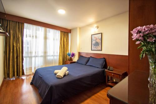 a bedroom with a bed and a vase of flowers at Apartamentos Galerías in Bogotá