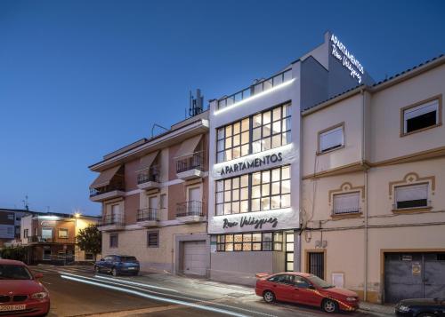 un edificio con un coche rojo estacionado frente a él en Apartamentos Rosa Velázquez en Mérida