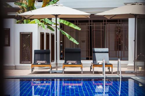 two chairs and umbrellas next to a swimming pool at Huernnana Boutique Hotel in Phrae