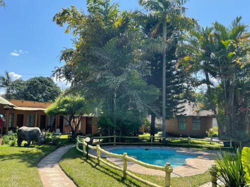 a house with a pool and a cow in a yard at REED MAT LODGE in Lusaka
